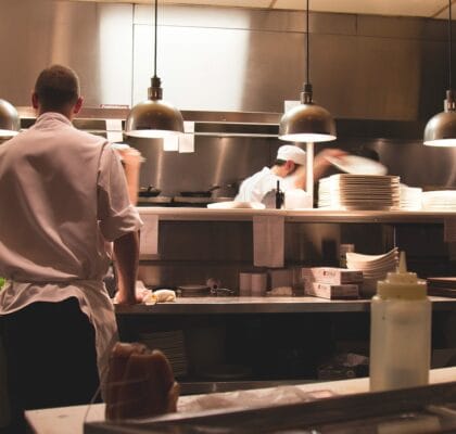 personel portant une veste de cuisine dans une cuisine avec hotte professionnelle